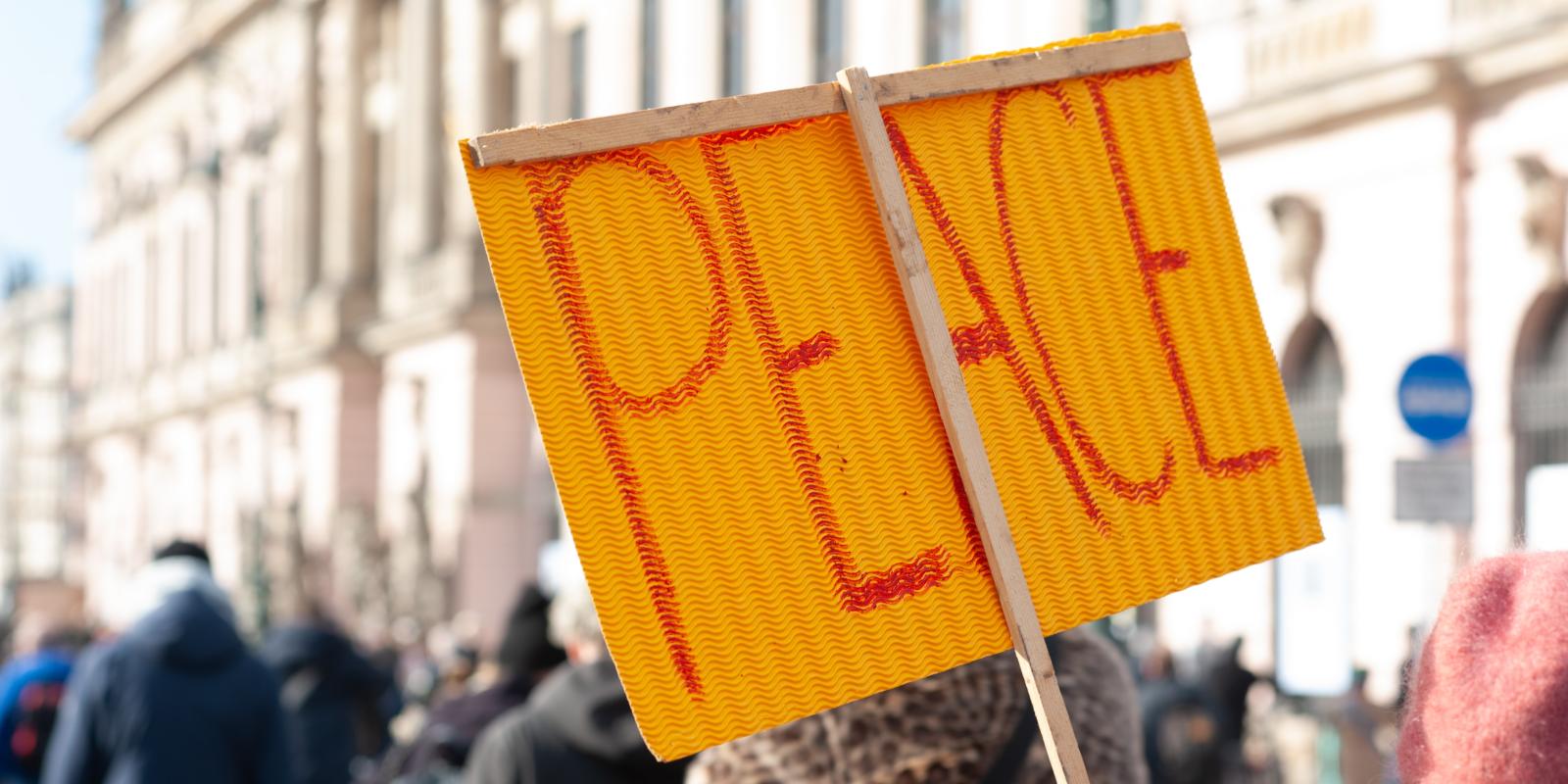 Peace written on a sign held up in a crowd